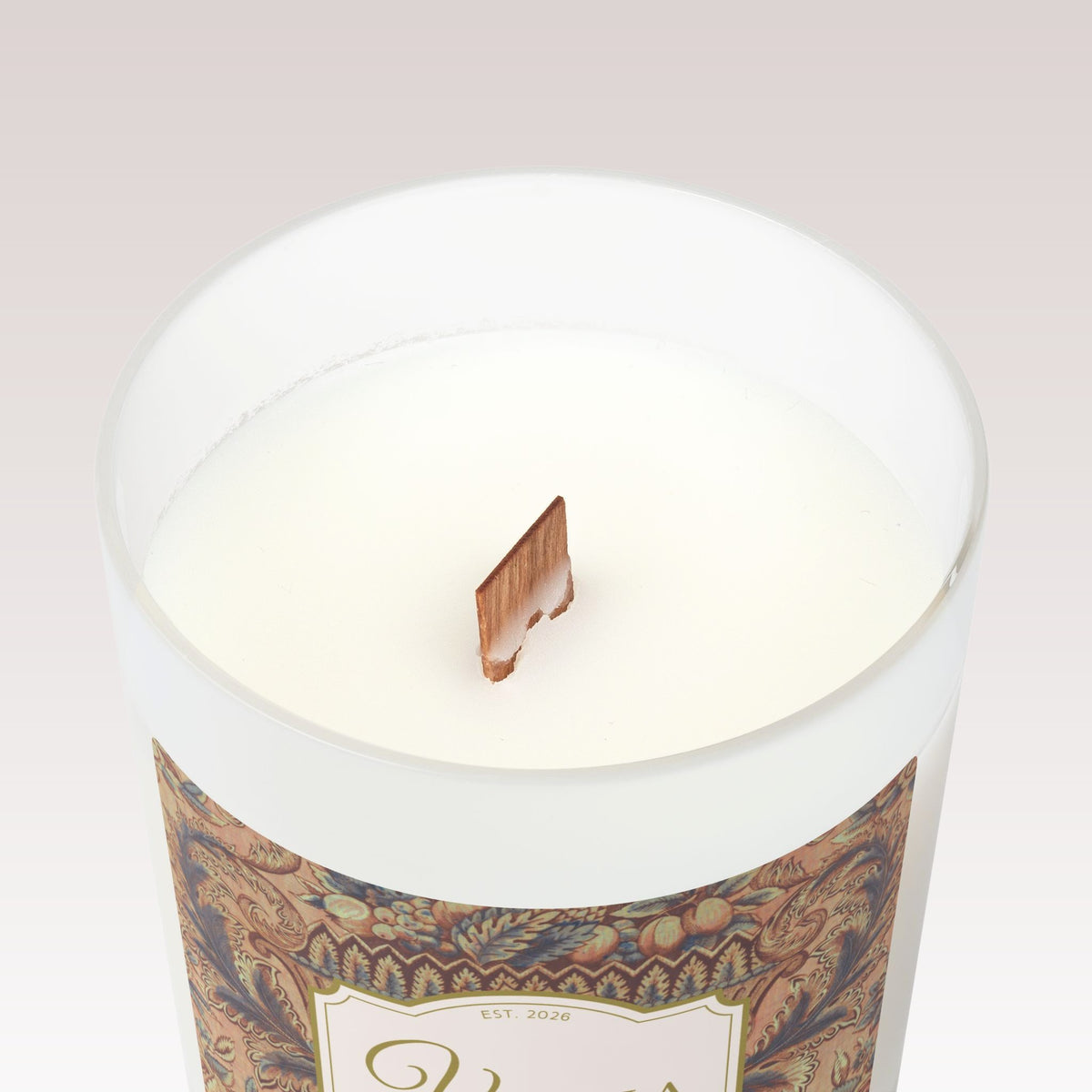 A close-up top view of a white candle in a frosted glass jar with a single wooden wick. 