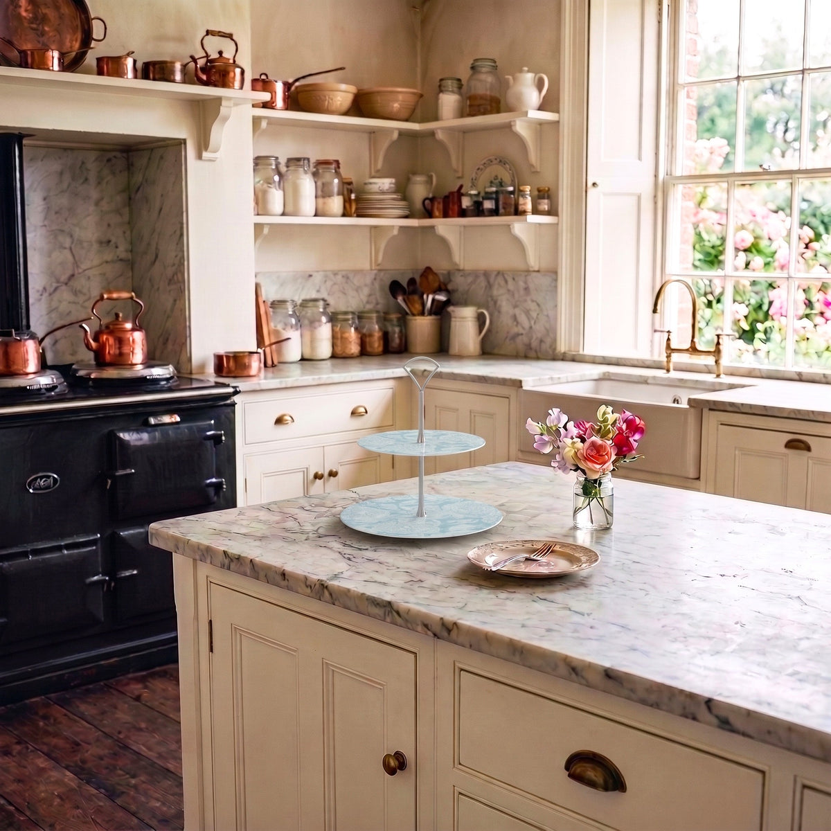 A decorative tiered cake stand sits on a marble bench in a classic vintage styled kitchen.